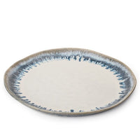 The Simon Pearce Burlington Dinnerware Pool is a round ceramic plate with a glazed, slightly uneven edge, a white center, and a blue-gray speckled rim, shown against a plain white background.