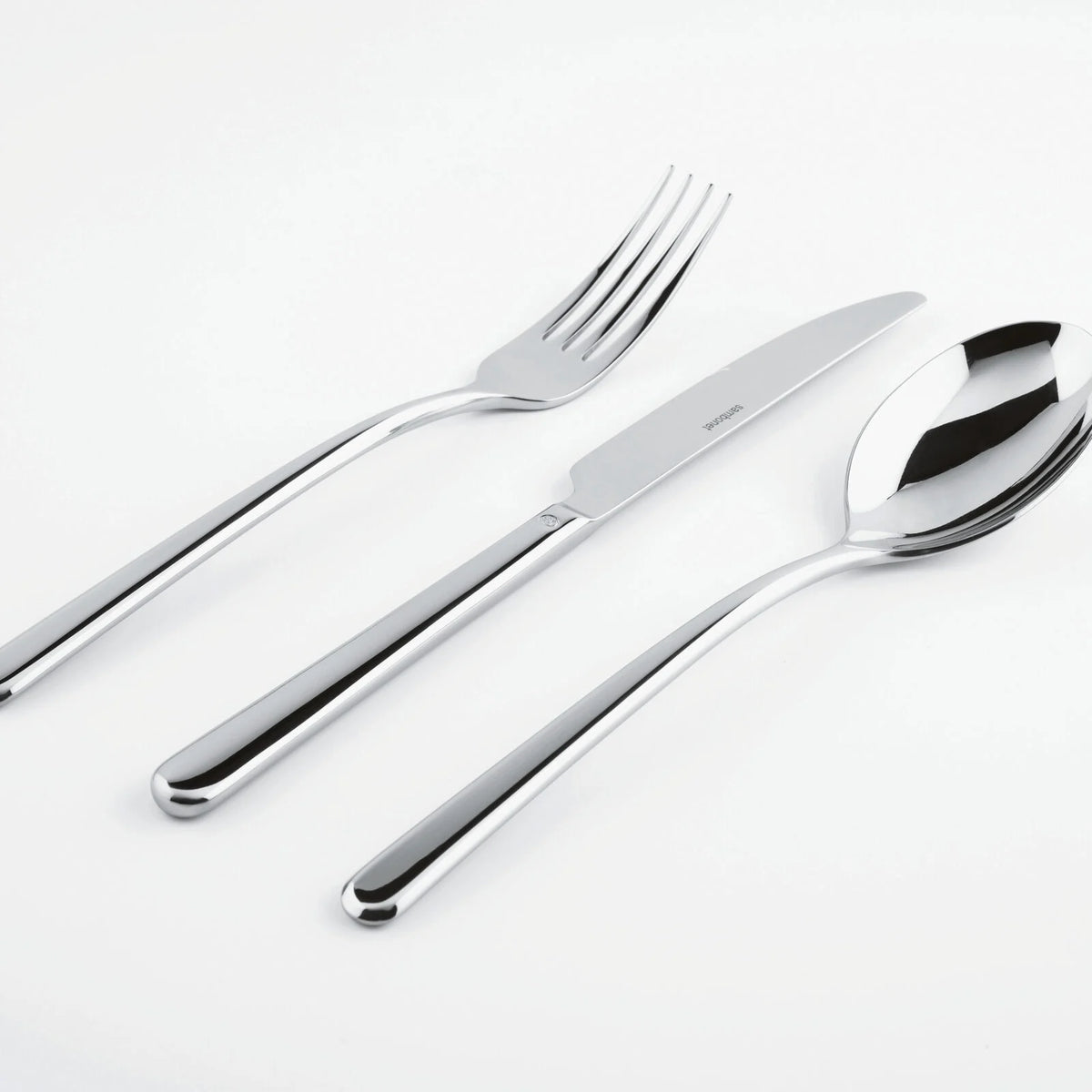 The Sambonet Linear Solid Handle Flatware 5 Place Setting—featuring sleek modern design—is artfully displayed side by side on a white surface.