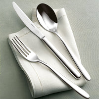 The Sambonet Hannah Flatware 5 Piece Setting in stainless steel is elegantly displayed on a folded white cloth napkin atop a pale green tablecloth.