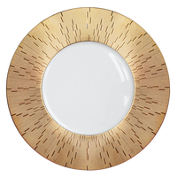 The Infini Prestige Gold Dinnerware by Haviland features a striking sunburst pattern around a white center, inspired by hand-painted Limoges porcelain.