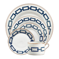 The Ginori 1735 Catene Zaffiro Dinnerware is a five-piece porcelain set with blue chain patterns and gold rims, including a dinner plate, salad plate, bread plate, saucer, and an elegant handled teacup.