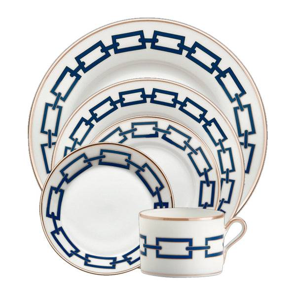 The Ginori 1735 Catene Zaffiro Dinnerware is a five-piece porcelain set with blue chain patterns and gold rims, including a dinner plate, salad plate, bread plate, saucer, and an elegant handled teacup.