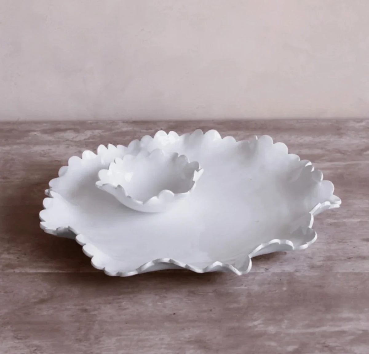 The Beatriz Ball Vida Colette Round Platter with Mini Dip Bowl in white sits on a wooden surface, its scalloped edges and matching bowl making it perfect outdoor serveware against a light beige background.