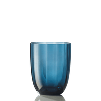 The Idra Tumbler Optic by Nason Moretti is a translucent blue glass with smooth, rounded sides, shown upright on a white reflective surface against a plain white background.