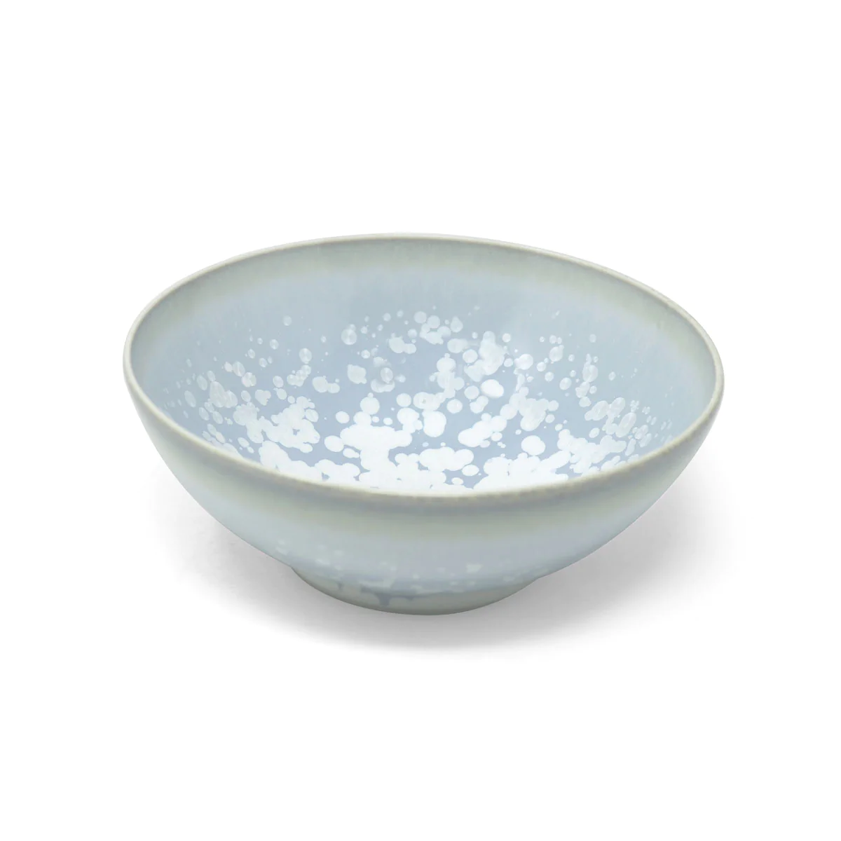 The Song Ocean Dinnerware by Jaune De Chrome is a round, shallow ceramic bowl inspired by French style, with a pale blue glaze and white speckles inside, displayed on a plain white background.