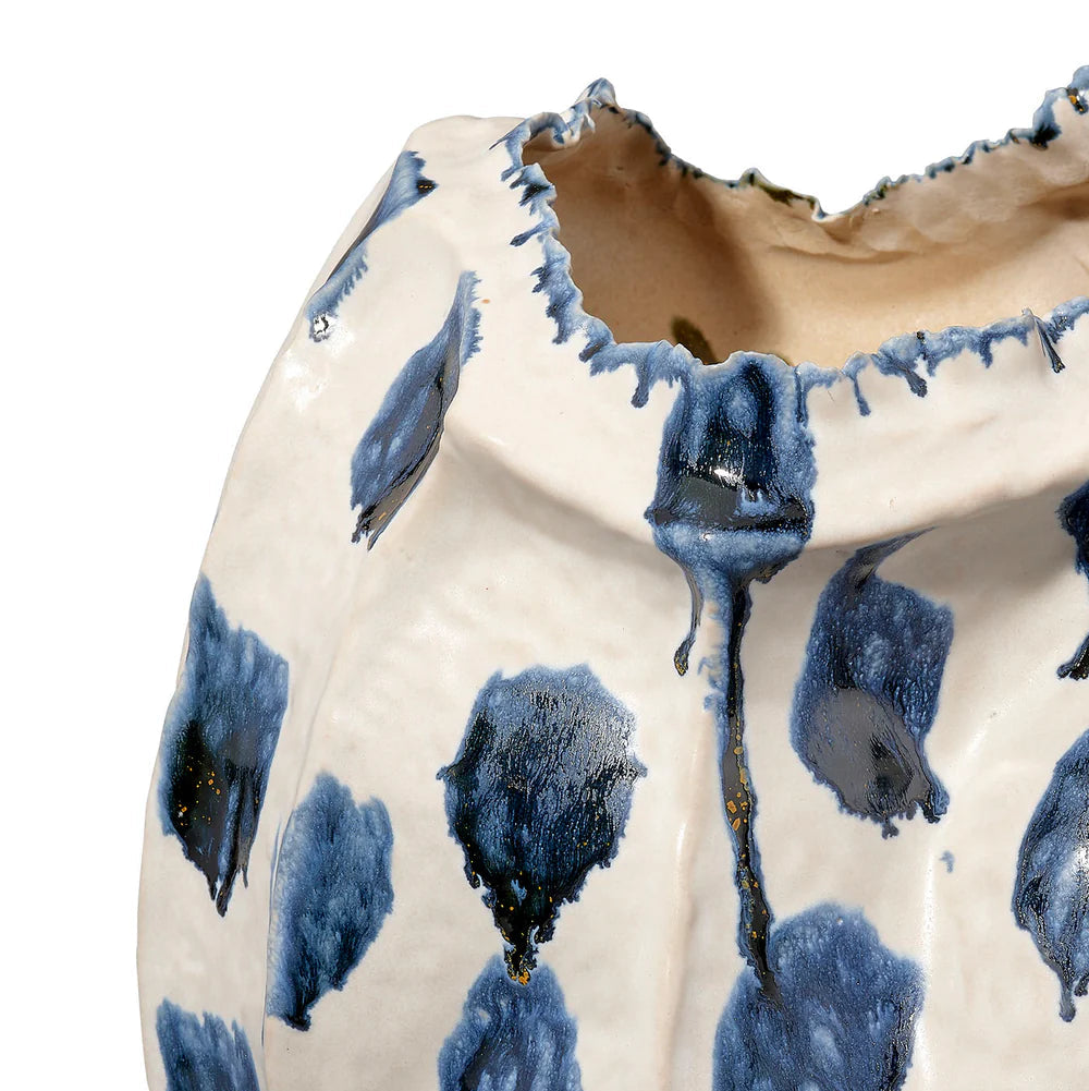Close-up of the Moncler Blue Vase by Jamie Young, a handcrafted ceramic piece with an irregular rim. Its white surface features abstract blue and gray brushstrokes and is finished with a glossy blue reactive glaze.