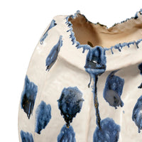 Close-up of the Moncler Blue Vase by Jamie Young, a handcrafted ceramic piece with an irregular rim. Its white surface features abstract blue and gray brushstrokes and is finished with a glossy blue reactive glaze.