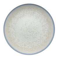 The Song Dinnerware Perle - Agoro plate by Jaune De Chrome is a round, high-fired porcelain piece with a speckled white pattern and light blue rim, shown from above on a plain white background for an elegant table setting.