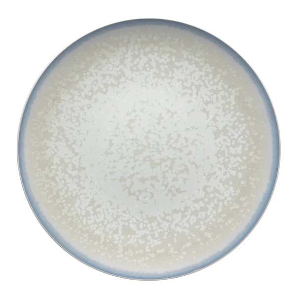 The Song Dinnerware Perle - Agoro plate by Jaune De Chrome is a round, high-fired porcelain piece with a speckled white pattern and light blue rim, shown from above on a plain white background for an elegant table setting.