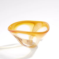 The Enigma Bowl – Amber by Global Views / Surya features organic, smooth, and asymmetrical curves in art glass. Set against a plain white background, light reflections accentuate its translucent, glossy surface, making this piece a striking decorative catchall.