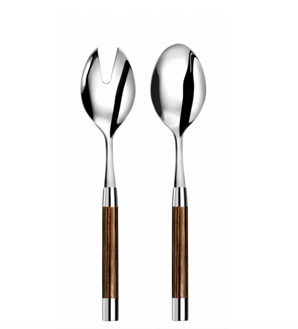 The Capdeco Conty Wood Salad Server Set features a fork with a V-shaped slot and a spoon, each with stainless steel tops and caramel-finished wooden handles, both standing upright against a white background.