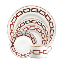 The Ginori 1735 Catene Scarlatto Dinnerware is a five-piece white porcelain set with red chain motifs and gold trim, including three plates, a bowl, and a handled teacup from the Ginori Collection.