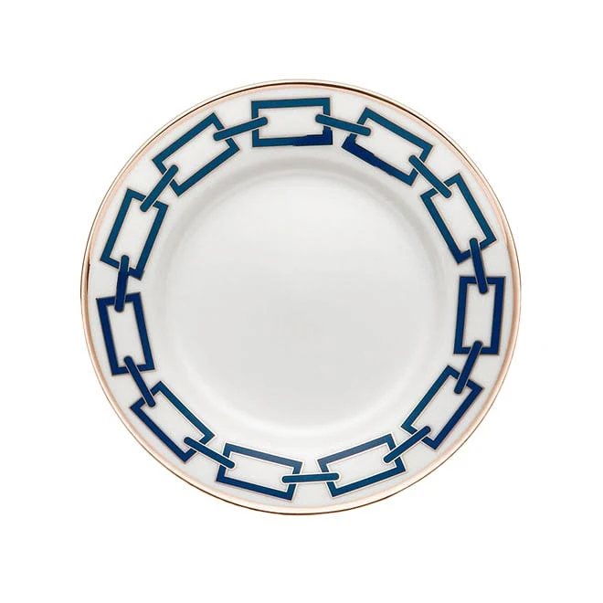 The Catene Zaffiro Dinnerware by Ginori 1735 is a white porcelain plate with a blue rectangular chain pattern and a gold rim, inspired by Gio Ponti, shown on a white background.