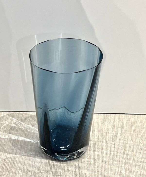 The Gary Bodker Optic Cups - Midnight - translucent blue hand-blown tumbler rests on a light textured surface with a white background and soft shadow.