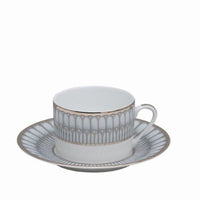 A white porcelain teacup with a small handle and matching saucer, both featuring Platinum Arcades designs by Philippe Deshoulieres BIA, sit centered against a plain background.