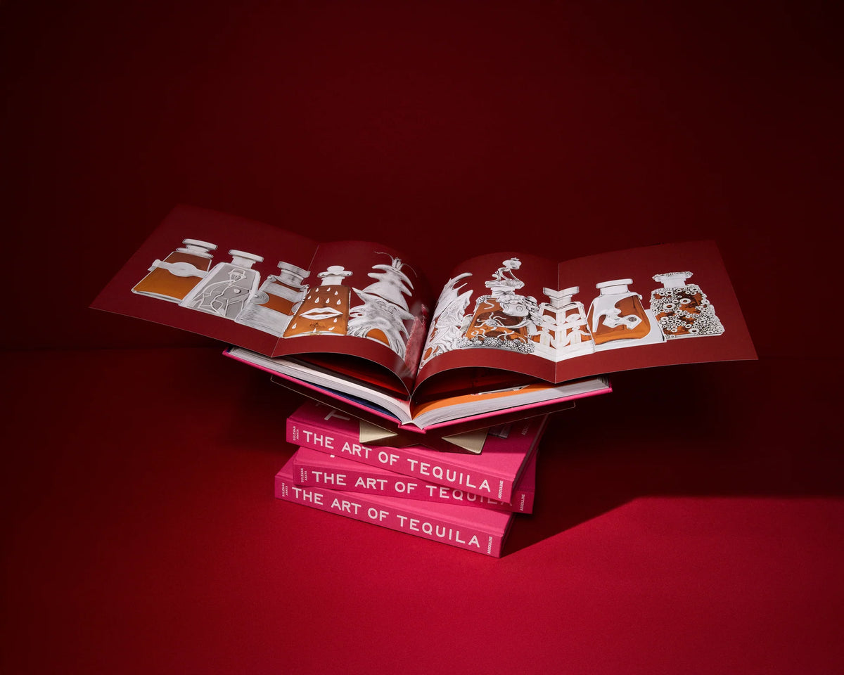 A stack of three hardcover copies of The Art of Tequila by Assouline, with a fourth book opened on top to display an accordion-fold illustration of collectible bottles against a dark red background.