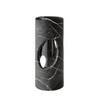 The modern cylindrical black marble side table with white veining and an oval cutout pairs elegantly with the Pietra Marble Vase by Greg Natale, creating a chic minimalist display against a plain white background.