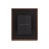 The Terreno Leather & Walnut Frame by Greg Natale features a dark walnut border and a black crocodile-patterned vegan leather inner section. A gold-lettered GREG NATALE placeholder card adds style to modern interior decor.