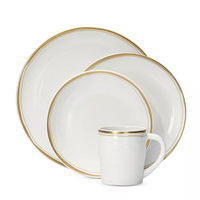 The Bernardaud Albatre Dinnerware - Gold set features a white alabaster dinner plate, salad plate, bowl, and mug with gold rims, arranged side by side against a plain background for understated wabi-sabi elegance.