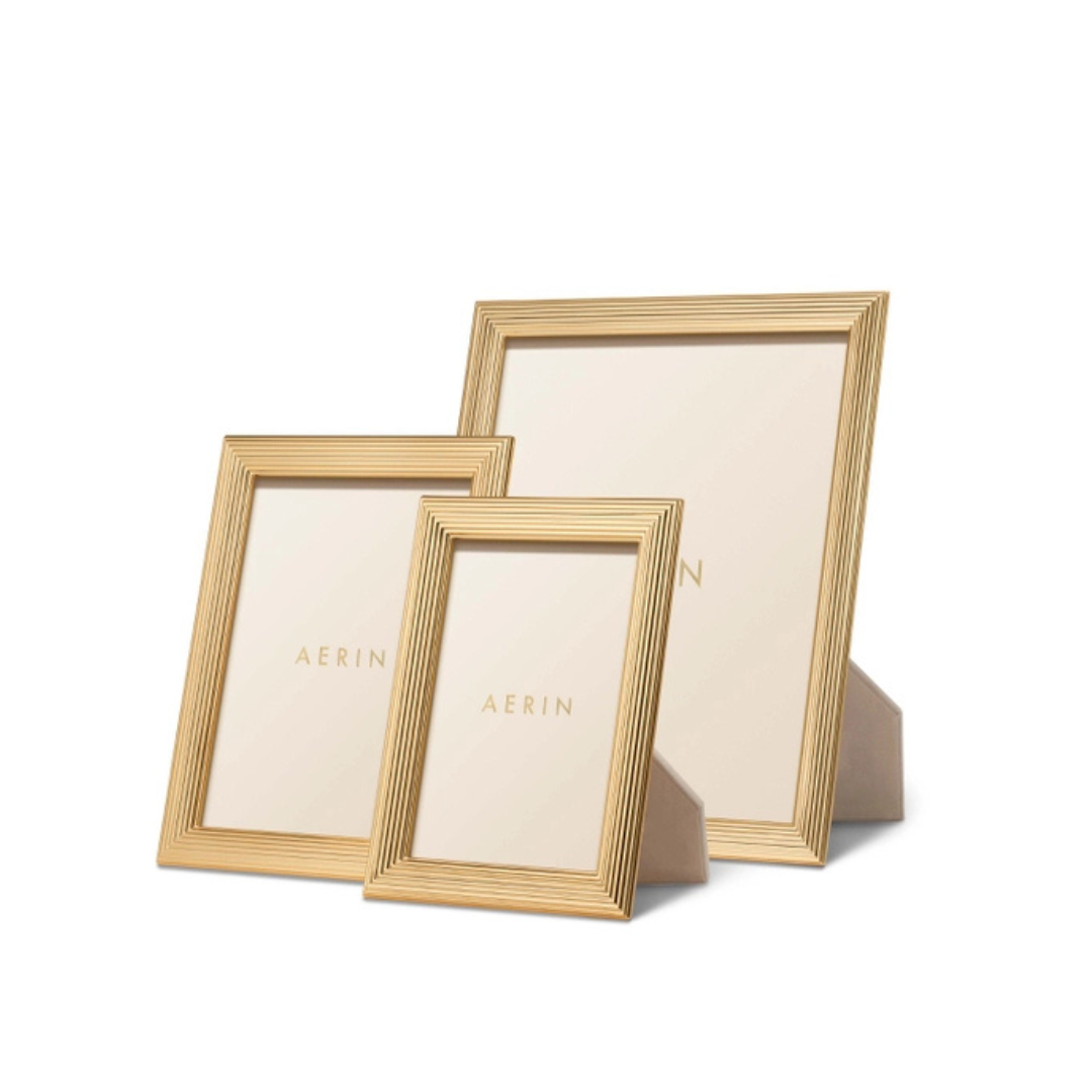 Three Alessio Frames by Aerin, gold-edged with a reeded design in assorted sizes, stand upright against a white background. Each displays the Aerin name on its insert.