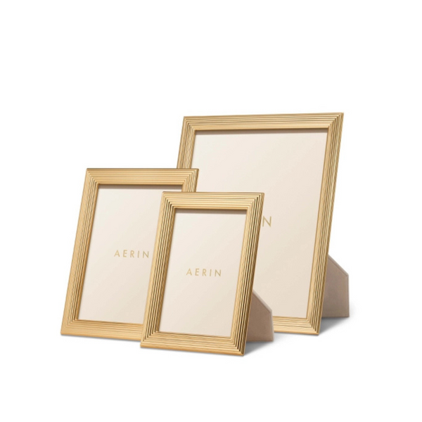 Three Alessio Frames by Aerin, gold-edged with a reeded design in assorted sizes, stand upright against a white background. Each displays the Aerin name on its insert.