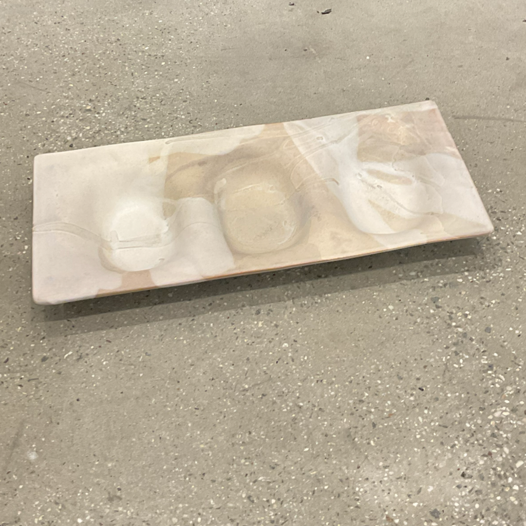 The Three Part Stone Rectangle Platter by Alex Marshall Studios is a handmade ceramic piece with smooth, wavy indentations and a pale marbled beige finish, shown resting on a speckled concrete floor.