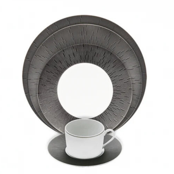 A modern Haviland Anthracite Infini Dinnerware Grey set features a white cup and saucer alongside two round plates with a dark gray, finely lined radial pattern. Made from Limoges porcelain, it stands out against the white background.