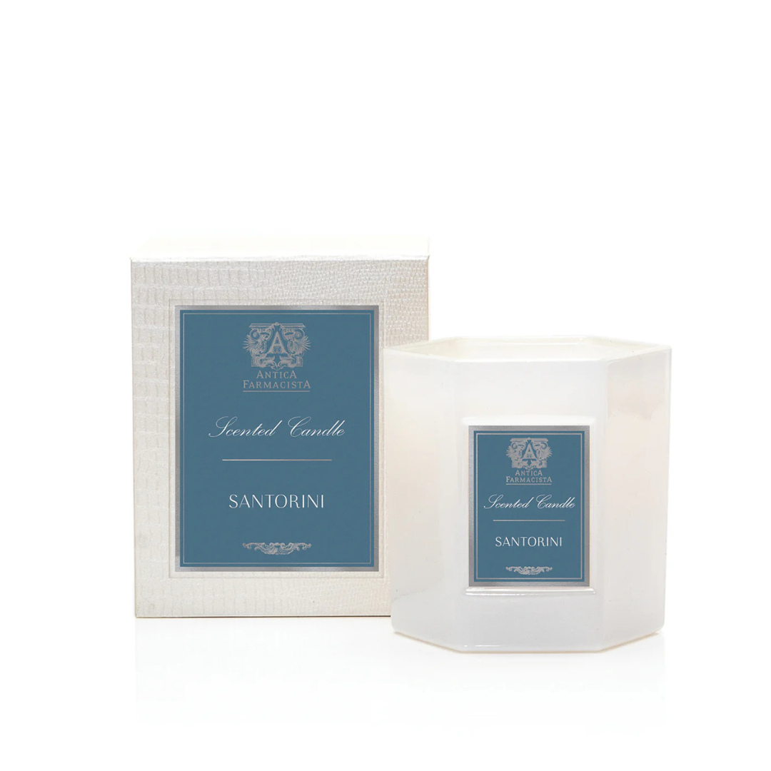 The Santorini Candle by Antica Farmacista/Harper is a white, octagonal soy-paraffin candle with a blue label and ornate design, paired with its matching box—evoking a Mediterranean scent experience.