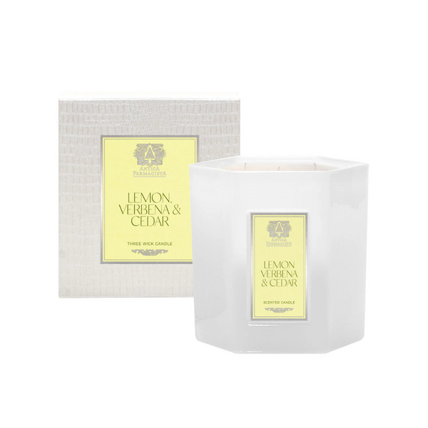 A white hexagonal Antica Farmacista/Harper Lemon Verbena & Cedar Candle sits before a matching textured box with a yellow label displaying the scent name and decorative emblem.