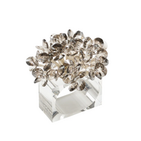 The Aster Napkin Ring Set of 4 by Kim Seybert features clear, rectangular beading with a cluster of faceted, smoky crystal petals on top, bringing an elegant, sparkling floral accent to your table decor.