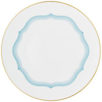 The Aura Dinnerware by Raynaud is a white dinner plate with a gold rim and a wavy blue line border near the center, showcasing contemporary design.