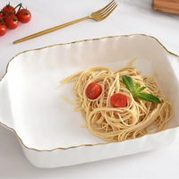 The PAMPA BAY Portofino Square Baker holds a small serving of plain spaghetti, garnished with cherry tomato halves and mint. A gold fork and extra cherry tomatoes are placed on the white surface beside the baker.