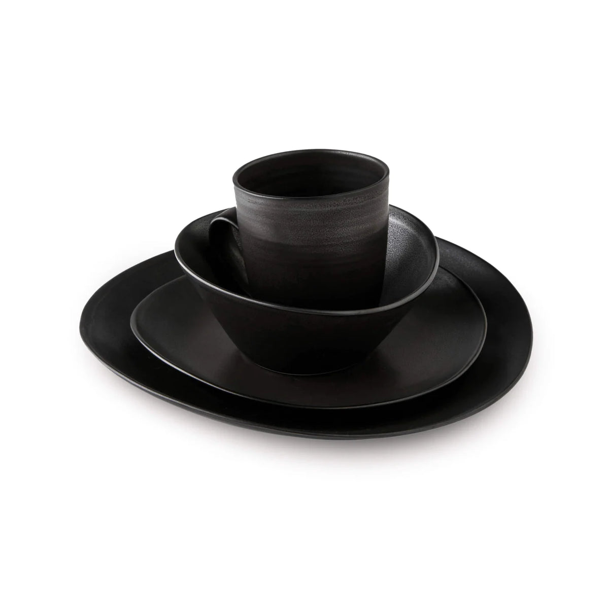 A stack of Simon Pearce Barre Dinnerware Slate stoneware dishes with a matching mug, all in matte black, from the modern dinnerware set, displayed on a white background.