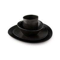 A stack of Simon Pearce Barre Dinnerware Slate stoneware dishes with a matching mug, all in matte black, from the modern dinnerware set, displayed on a white background.