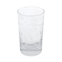 A Mariposa Bellini Glassware tumbler, featuring small bubbles and textured imperfections, stands upright on a white background, partially filled with water.