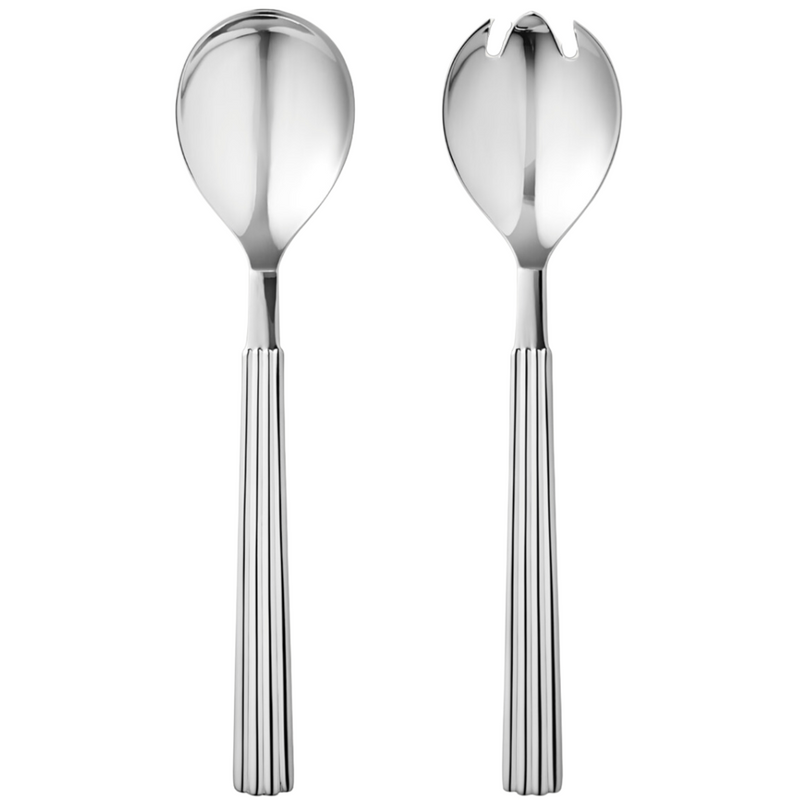 Two silver utensils—a large spoon and a matching two-pronged fork—from the Georg Jensen Bernadotte Salad Server Set stand upright against a white background, highlighting their timeless Scandinavian design.