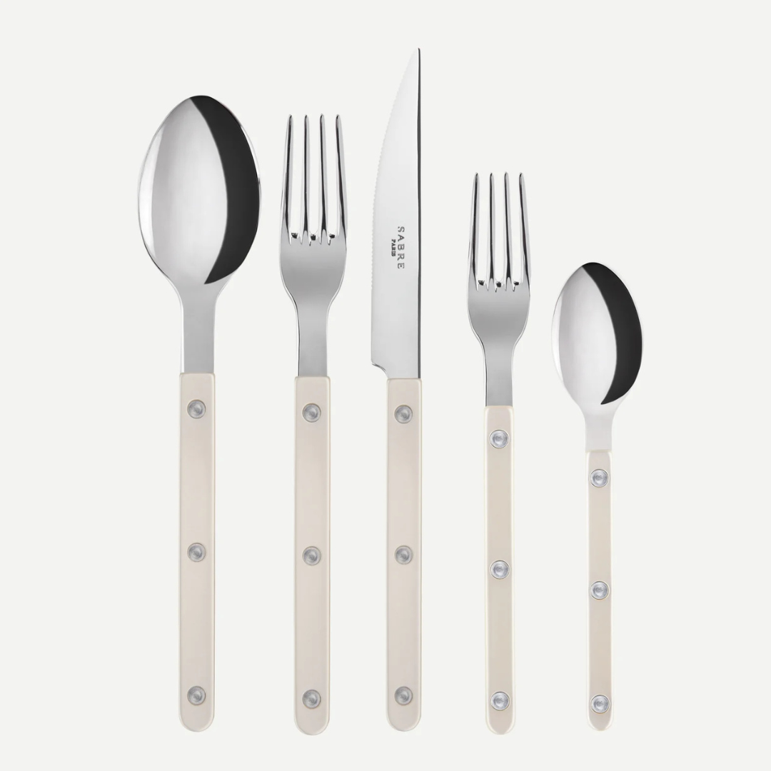 The Sabre Bistrot Pearly 5 Piece Setting - Shiny includes a tablespoon, dinner knife, dinner fork, salad fork, and teaspoon—each with cream mother-of-pearl handles and metal rivets—shown upright on a white background.