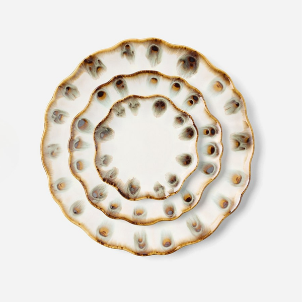 Three scalloped ceramic plates from Blue Pheasant’s Amoria Dinnerware collection, featuring a white base and brown, blue, and beige speckled edges, are stacked concentrically on a plain light background—these pieces of scalloped edge serveware showcase vintage-inspired elegance enhanced by a subtle reactive glaze.