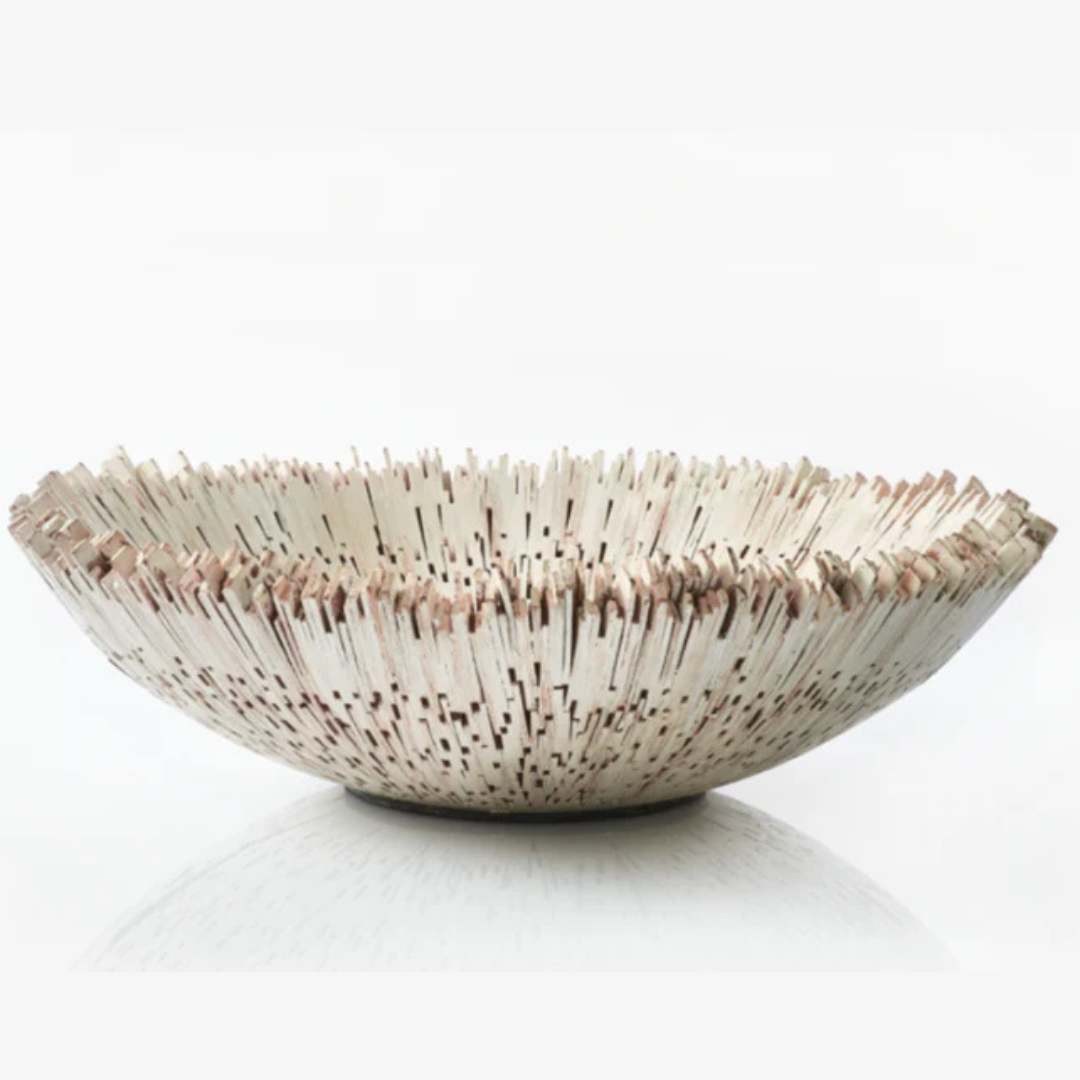 The Boracay Centerpiece Ivory Bowl by Lily Juliet is a round, shallow ceramic bowl featuring vertical white and brown textured ridges radiating from the center, its artisan design inspired by sea urchin spines.