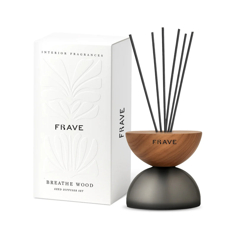 A Frave Home Breath Wood Frosted Glass Diffuser - Elderflower, in a modern half-wood, half-gray glass design with black reeds, is shown beside its white packaging embossed with botanical patterns.