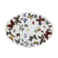 The Vista Alegre Butterfly Parade Dinnerware showcases an oval white plate adorned with vibrant butterfly illustrations in assorted sizes and colors, creating a striking decorative pattern.