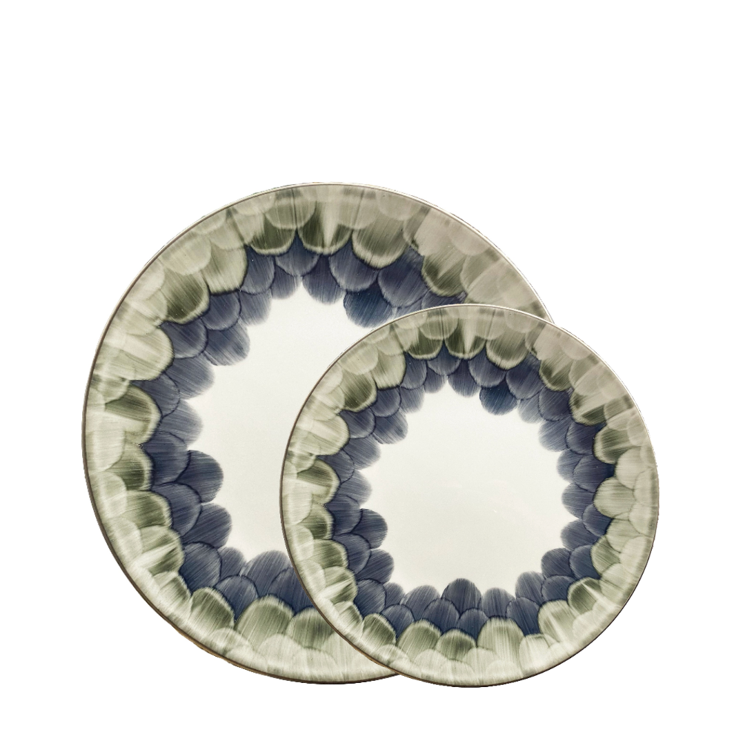 Two Marie Daâge Cercle d'Ecailles Dessert Plates, crafted in ceramic with hand-painted blue and green scalloped rims, overlap on a white background—showcasing the brand’s elegant artistry.