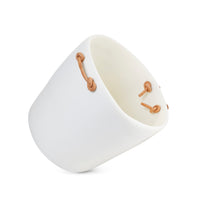 The Tina Frey Champagne Bucket Leather Handle is a white, oval ceramic piece with tan leather handles threaded through side holes, shown angled on a white background.
