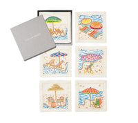 The Kim Seybert Cocktail Napkin Set of 4 – Sunny Isles features embroidered beach scenes, making a charming hostess gift. Arrives in a grey Kim Seybert box—perfect linen napkins for your next summer gathering.