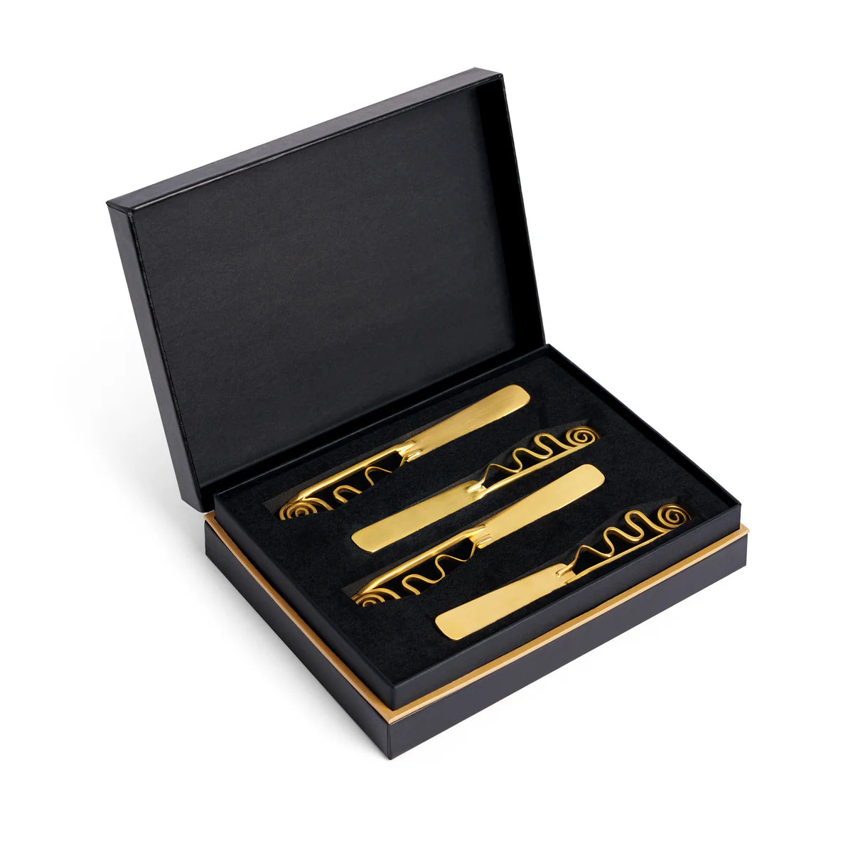The L'Objet Spirale Gold Spreaders Set of 4 features four 24k gold-finished spreaders in wavy and spiral designs, elegantly arranged in a black box with gold trim—an exquisite luxury tableware addition.