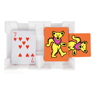 A 7 of hearts playing card sits beside two orange Canasta Sets cards, each decorated with a yellow bear in a pink collar, all neatly arranged in a white tray.
