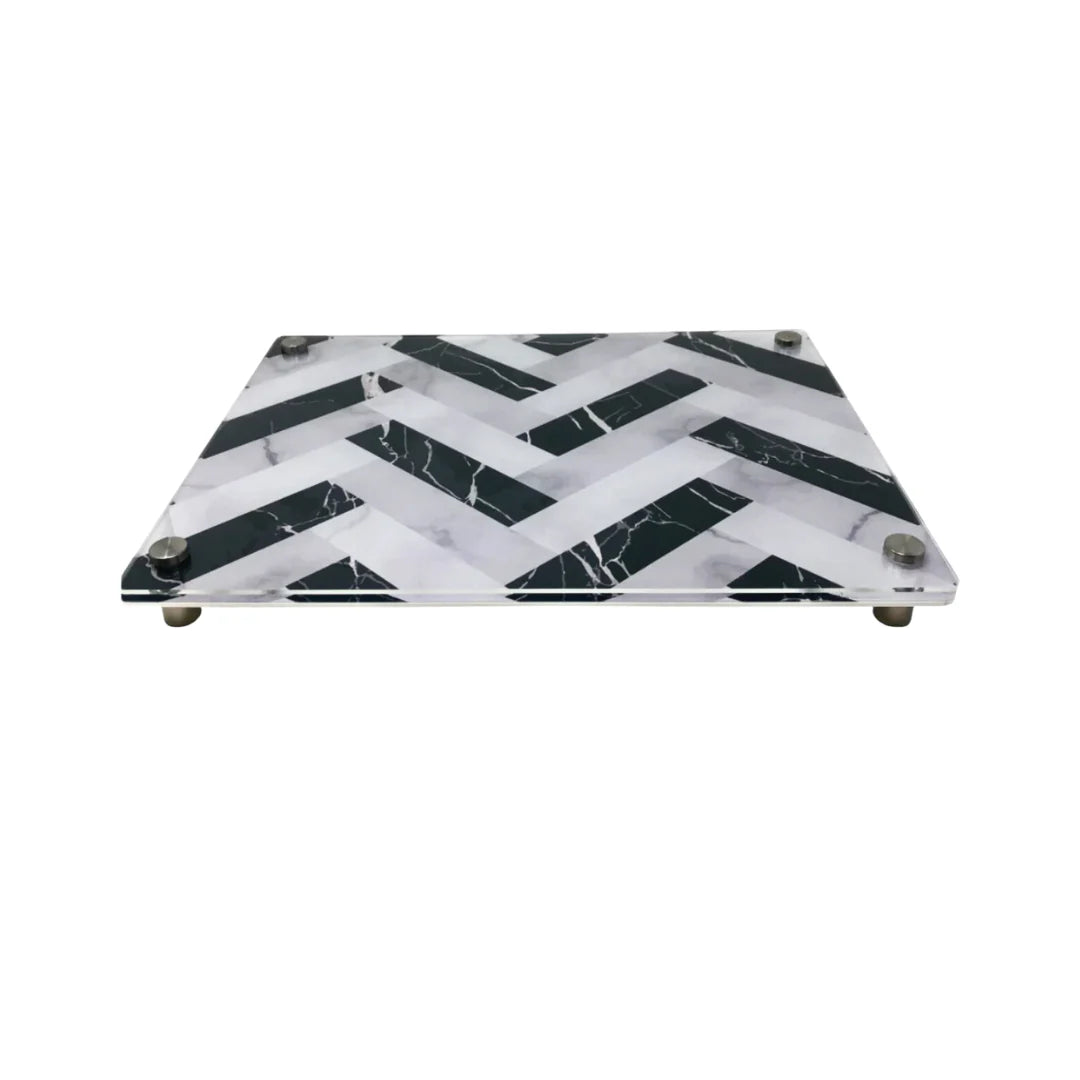 The Eye Candy Raised Serving Board Marble features a black and white chevron pattern and sturdy metal feet—a stylish choice for serving sushi or as a modern challah board.