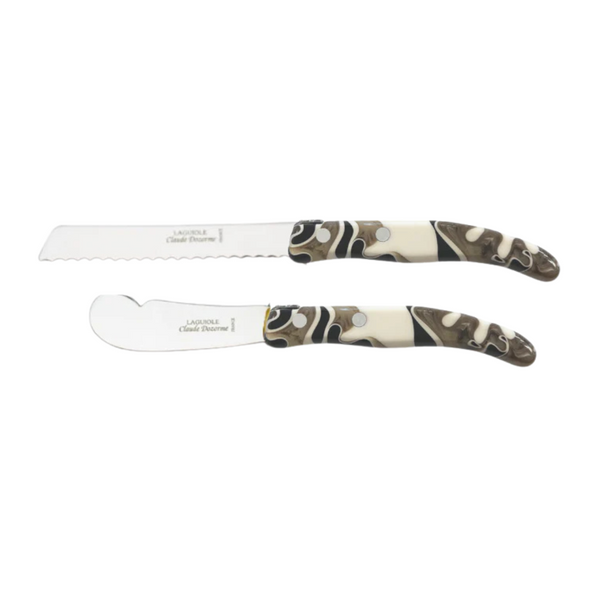 The Claude Dozorme Berlingot Ultimate Cheese Marble Design Set of 2 includes a serrated cheese knife and a wide-blade knife, both with patterned brown, white, and black handles and metal rivets—an elegant addition to any table.