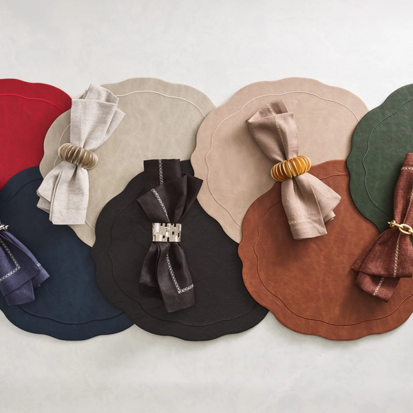 Kim Seybert's Classic Napkin - Earthtones Set of 4 is displayed atop overlapping scalloped-edge placemats, each finished with a decorative napkin ring for an elegant and refined table setting.