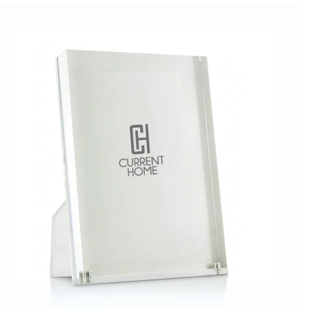 The Tizo Lucite Clear Frame is a simple, modern, and minimalist rectangular acrylic picture frame that stands upright on a white surface.